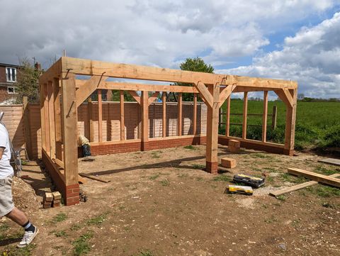 Newly raised structural oak garage frame in a garden plot under a blue sky