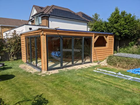 Timber garden room with glazed bi-fold doors on a sunny lawn