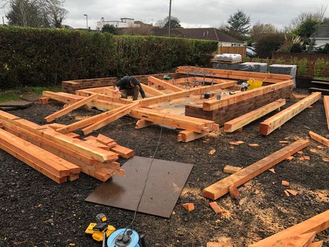 Carpenter fitting oak sole plates during a frame installation
