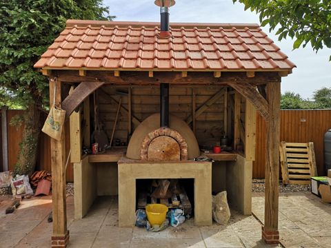 Oak-framed shelter with a tiled roof housing an outdoor pizza oven