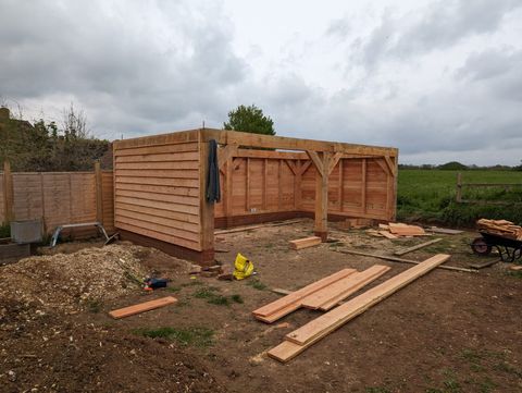 Timber garage part-clad in featheredge boards beside an open field