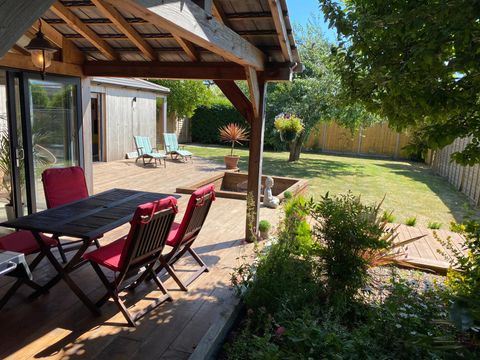 Sunlit decked seating area beneath an oak-framed veranda overlooking a lawned garden