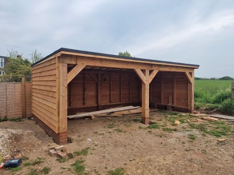 Open-fronted two-bay timber outbuilding beside a field