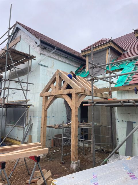 Carpenter fixing the roof structure of an oak porch on a new build home