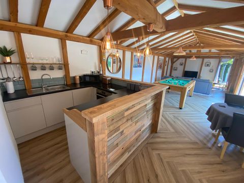 Open-plan interior with fitted kitchen, reclaimed-timber bar and exposed oak roof framing